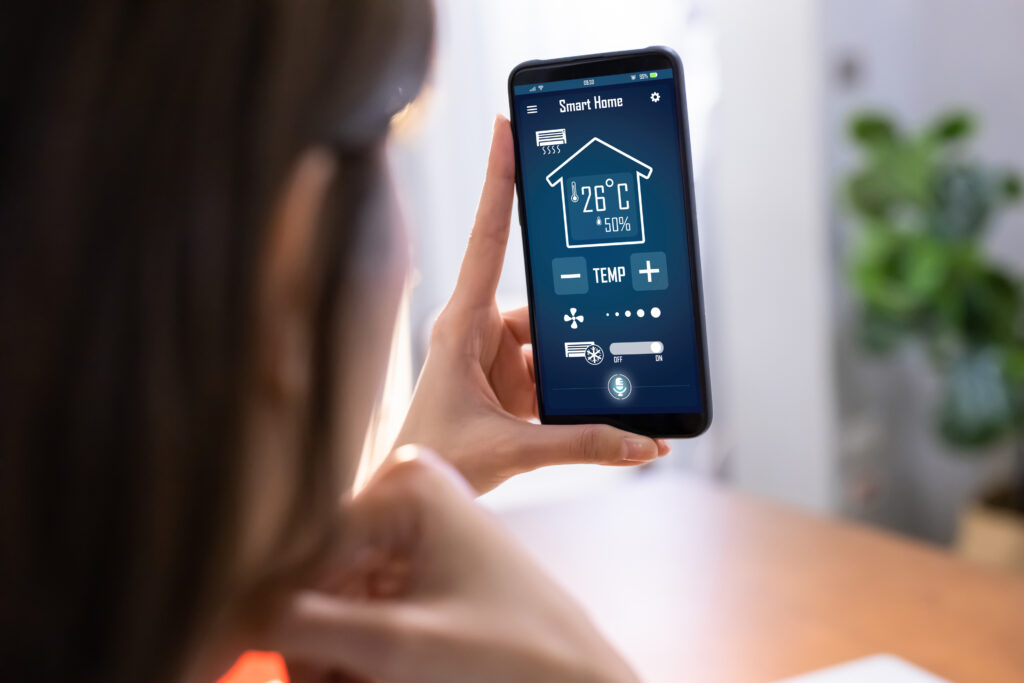 close up of asian young woman using smart home app on mobile phone to control air conditioner temperature. Evenly Heat Multiple Stories